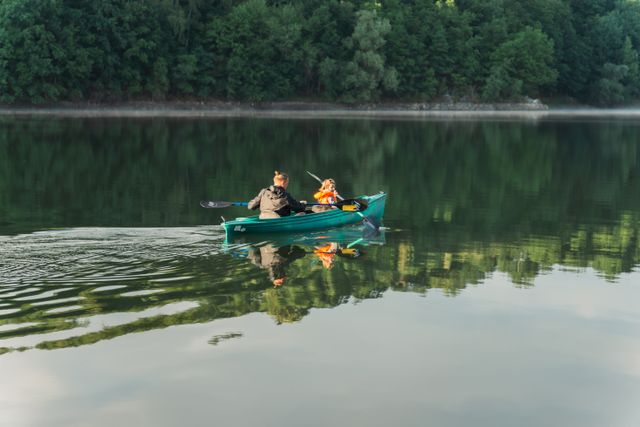 A couple enjoys kayaking on a tranquil green lake surrounded by lush trees in Germany.